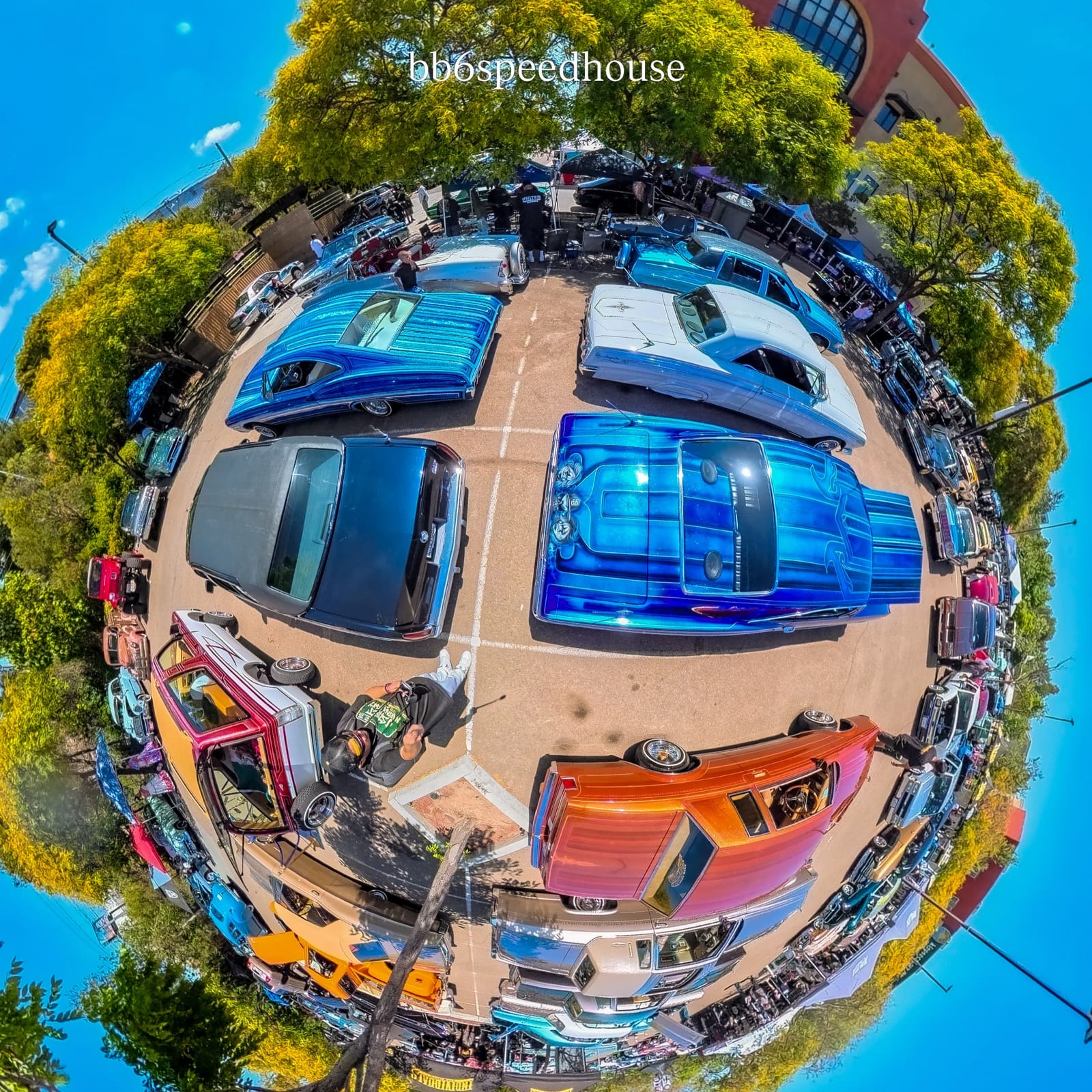 A fisheye view of custom lowriders gathered at a San Diego car show.